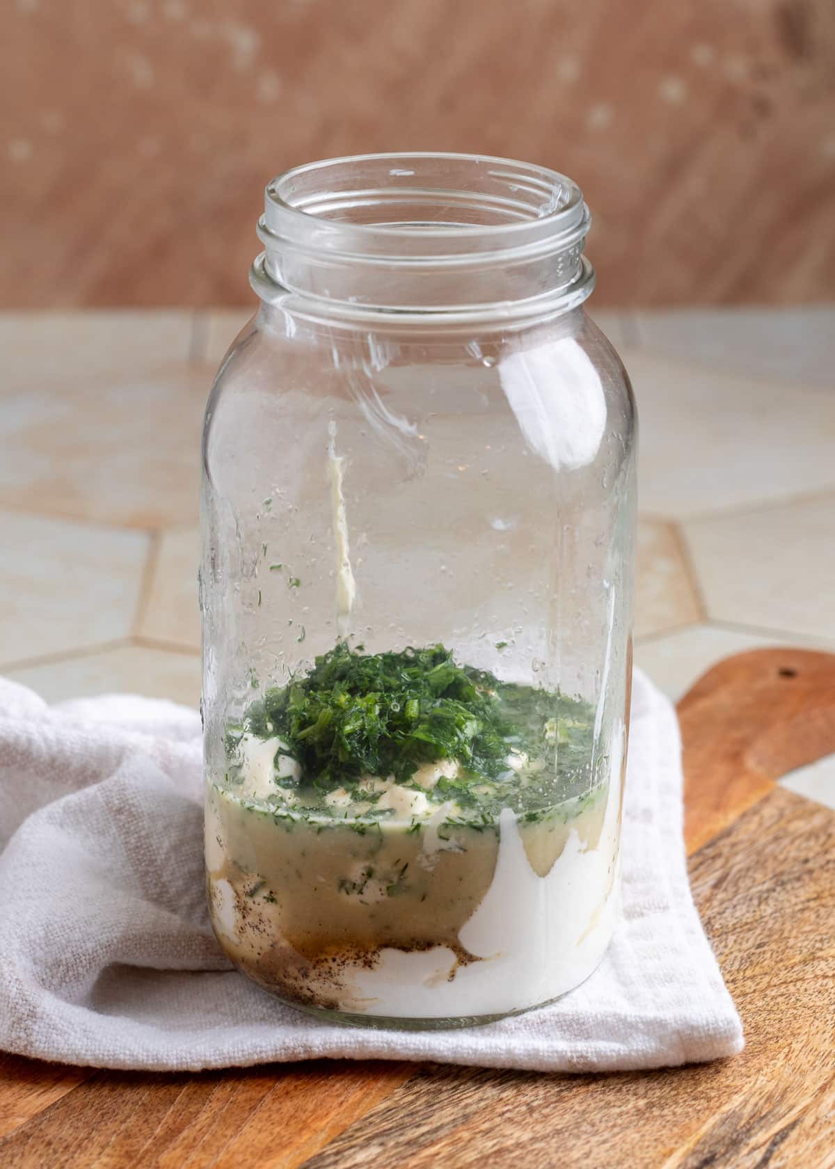 ingredients for ranch dressing in a mason jar on a wood board