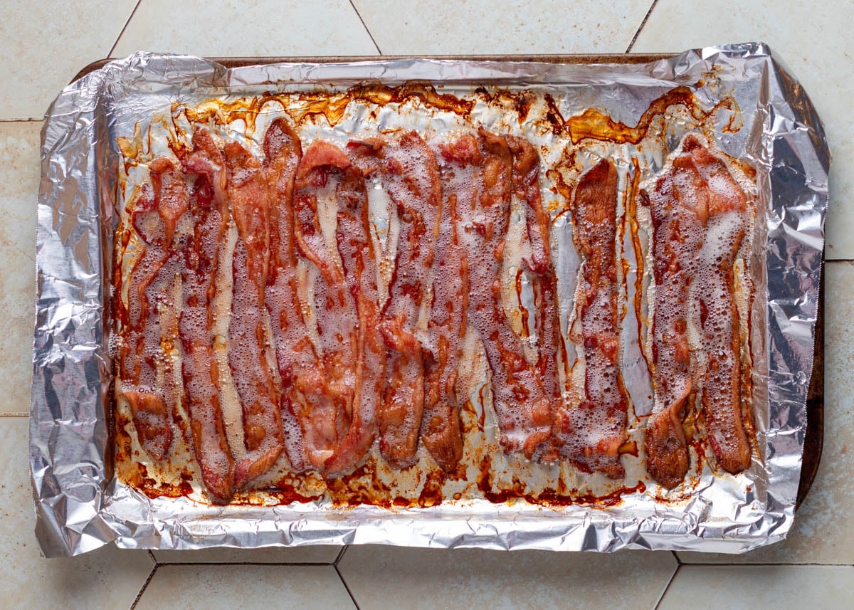 overhead of baked bacon on a foil lined baking sheet