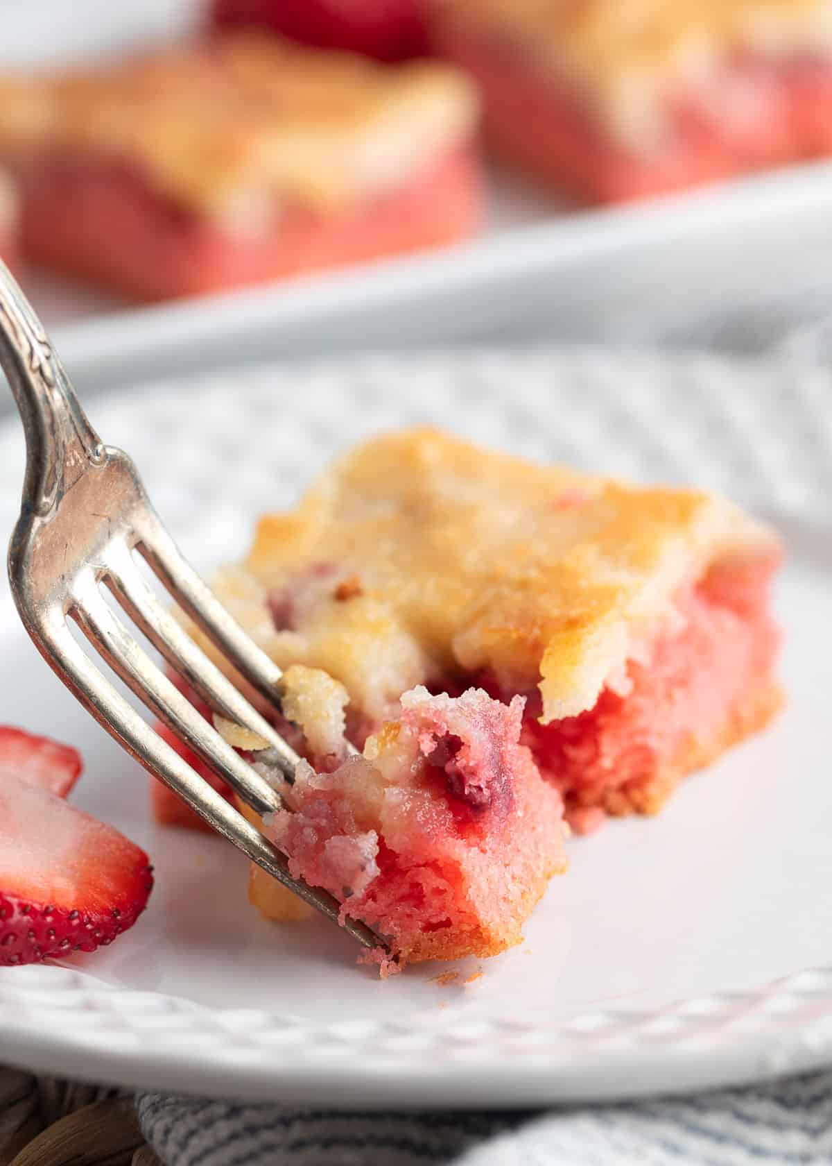 strawberry chess square on a white plate being cut into with a silver fork
