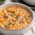 ham and bean soup in an ivory ceramic bowl garnished with fresh parsley