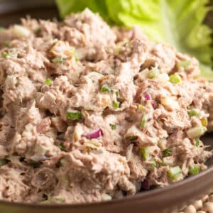 Close-up of apple tuna salad in a bowl, showing chunks of tuna, celery, apple, and red onion mixed in a creamy dressing.