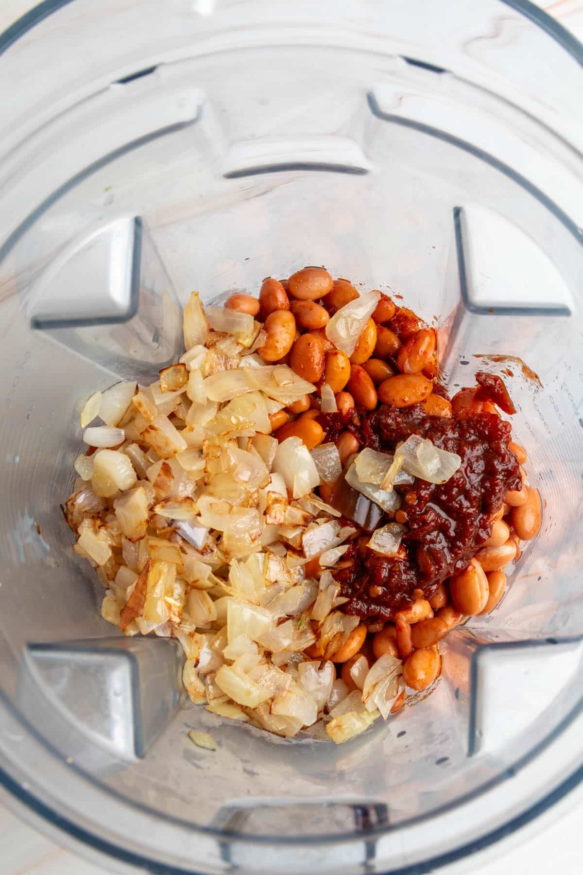 Blender filled with pinto beans, saut&eacute;ed onions, and chipotle in adobo sauce before blending.