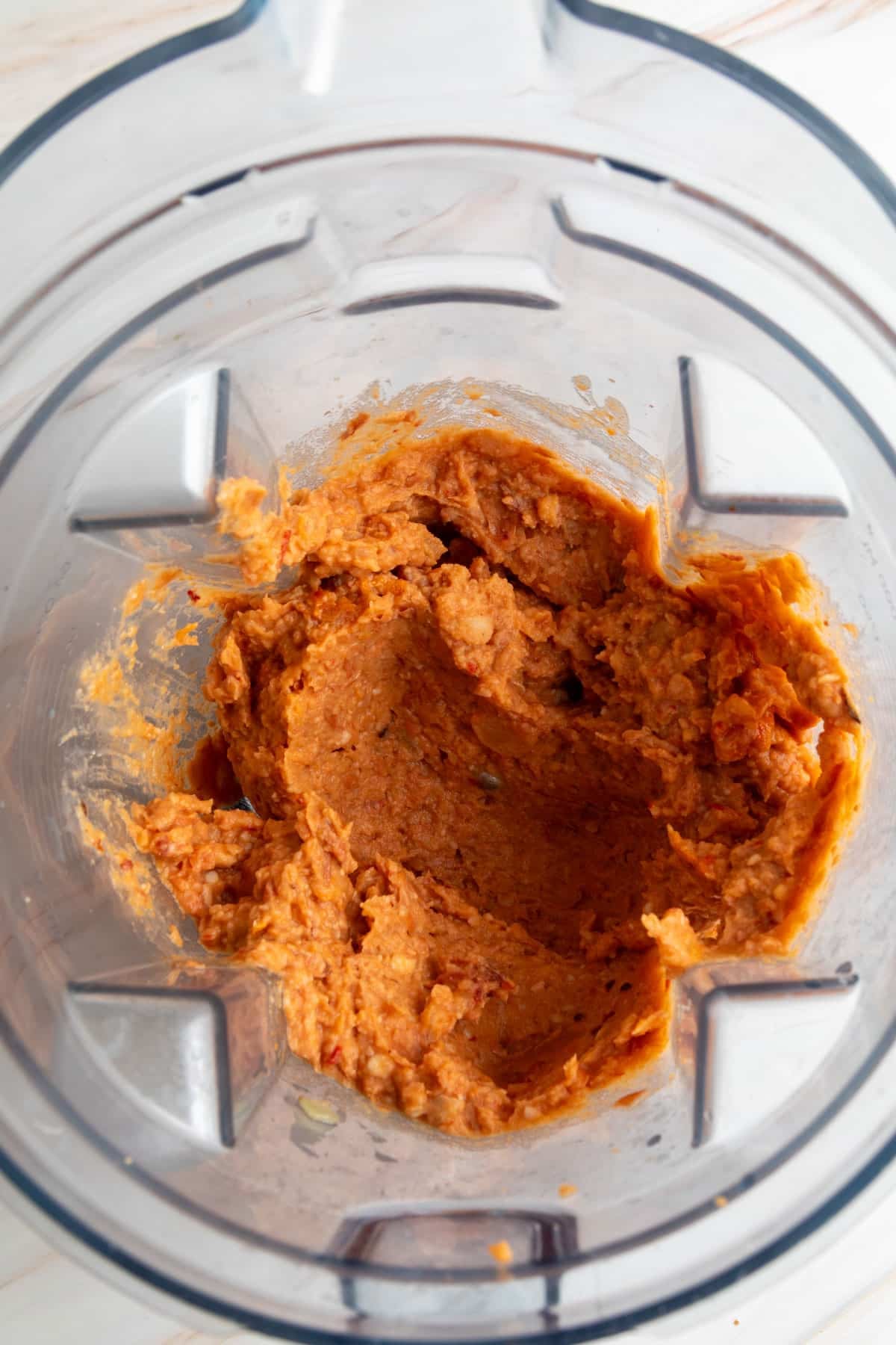 Blended chorizo bean mixture in a blender, smooth and thick with an orange-red color.